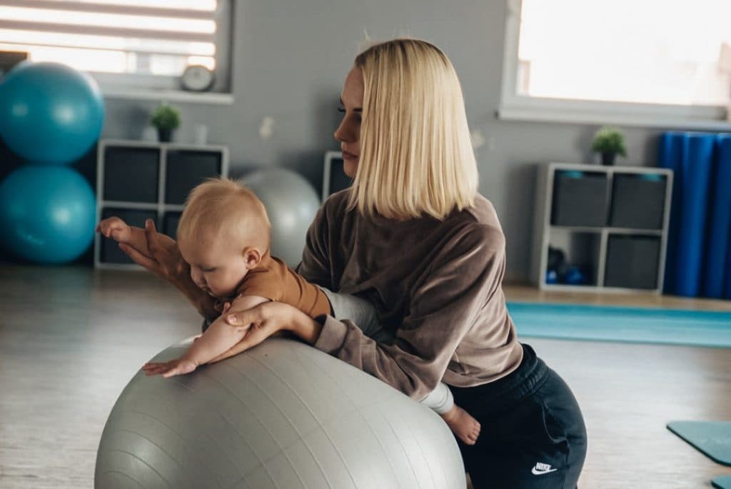 Mama su kūdikiu ant gimnastikos kamuolio studijoje